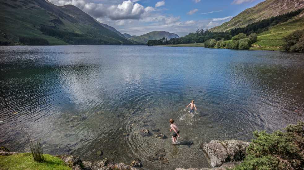 Socially distanced days out children swimming in lake Lake District